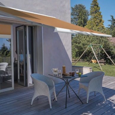 Un store-banne orange ouvert sur la terrasse d'une maison. Elle protège l'espace à manger extérieur.